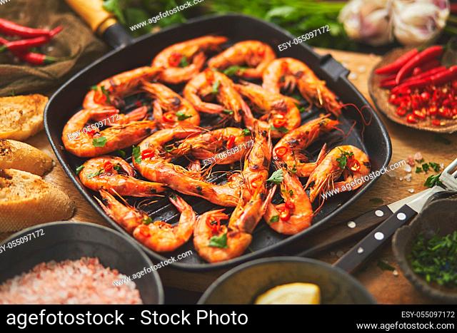 Tasty appetizing roasted shrimps prawns with spices on pan with ingredients on rusty background. Top View, flat lay. Background Seafood Kitchen Concept