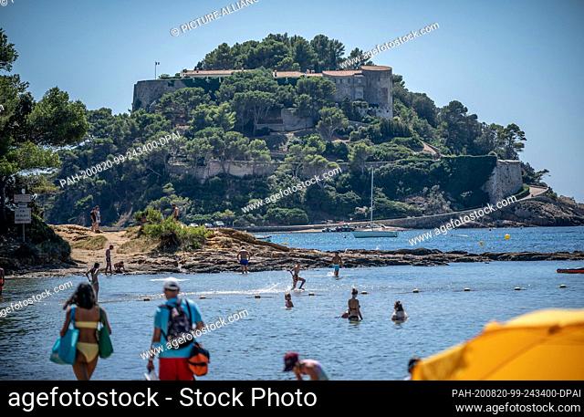 20 August 2020, France, Bormes-Les-Mimosas: Bathers are on the beach below the summer residence of the head of state, of France, Macron, the Fort de Bregancon