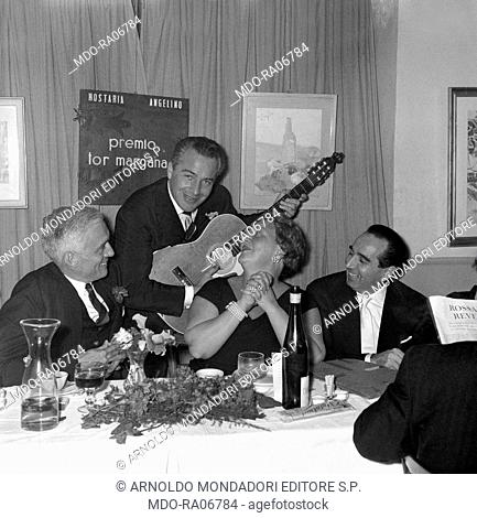 Italian actor Rossano Brazzi singing a serenade to his wife Lidia Bertolini during a dinner for the Tor Margana award ceremony at the Hosteria Angelino