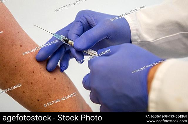 19 June 2020, Baden-Wuerttemberg, Tübingen: ILLUSTRATION - A man demonstrates how a woman is vaccinated in the Institute for Tropical Medicine at the University...