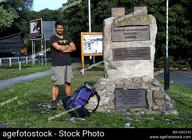Hiker, man with backpack at memorial stone Wall opening, border opening, Kolonnenweg, Lochplattenweg, inner German border, Stapelburg, Nordharz municipality