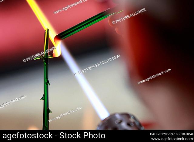 05 December 2023, Saxony-Anhalt, Derenburg: A glassmaker works at a flame and shapes a piece of glass. Glasmanufaktur Harzkristall GmbH is one of the few...