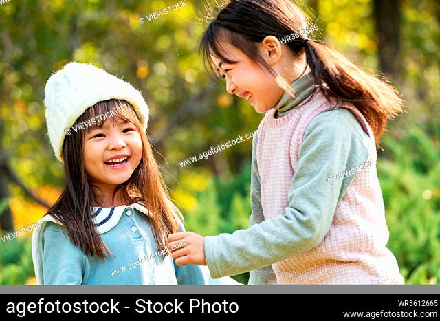Two happy little girl playing in the park