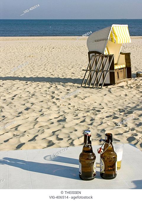 table with two bottles of beer and a glas on beach with beach chair and sea in background. - Mecklenburg-Vorpommern, Germany, 03/04/2007