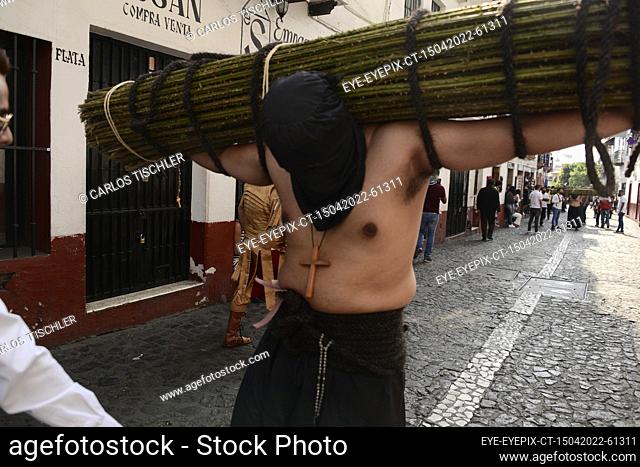 TAXCO, MEXICO - APR 15, 2022: A ‘E’ncruzado’ penitent wearing a black hood known as a capirotte, lifts a roll of blackberry thorns weighing 50kg