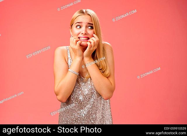 Lifestyle. Frightened insecure timid young blond woman afraid feel scared trembling fear stooping biting nails pop eyes right standing horrified red background...