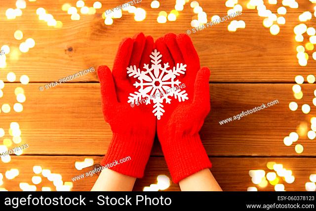hands in red woollen gloves holding big snowflake