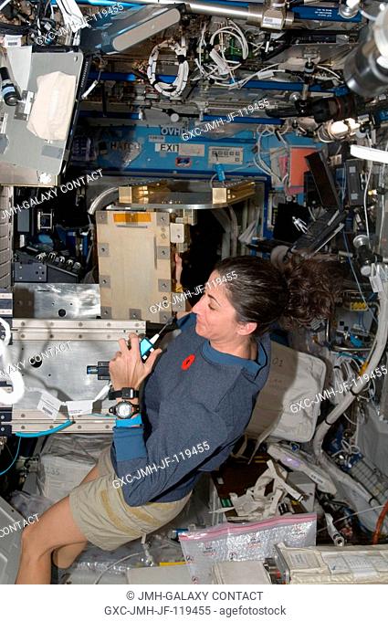 NASA astronaut Nicole Stott, Expedition 21 flight engineer, uses a communication system while installing the Light Microscopy Module (LMM) Spindle Bracket...