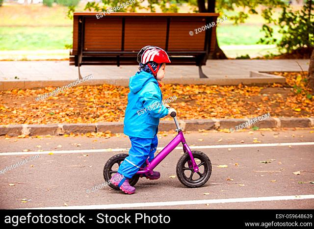 Three years boy is riding on balance bike at the cycle track, autumn walking