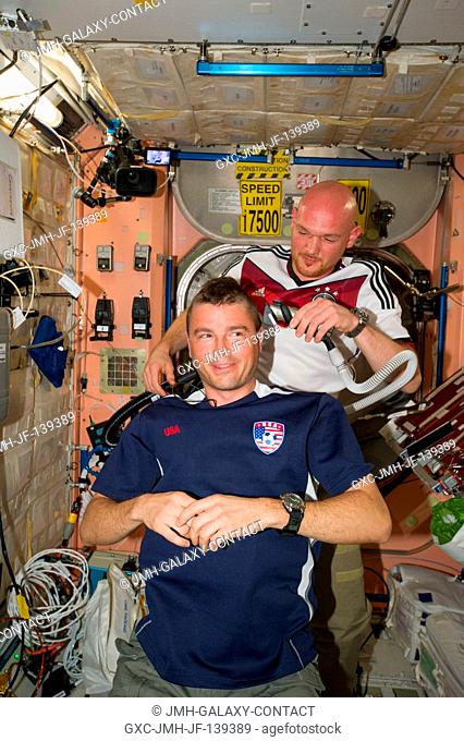 European Space Agency astronaut Alexander Gerst, Expedition 40 flight engineer, shaves the head of NASA astronaut Reid Wiseman, flight engineer