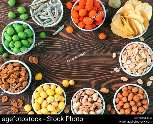 Assortment of different snack for beer, wine, party. Peanuts in coconut glaze, green vasabi, red spicy chilli, yellow cheese glaze, chips, pistachio, crackers