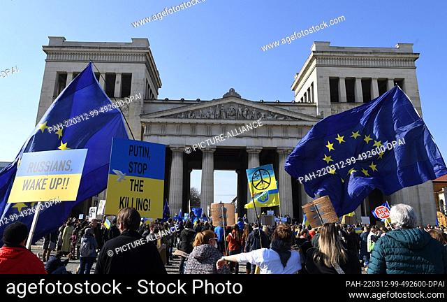 12 March 2022, Bavaria, Munich: Participants of a rally against the war in Ukraine demonstrate on the Königsplatz with European flags and signs with the...
