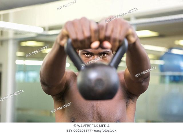Close-up portrait of shirtless man lifting kettle bell