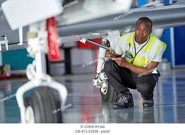 Ground crew worker with clipboard checking airplane