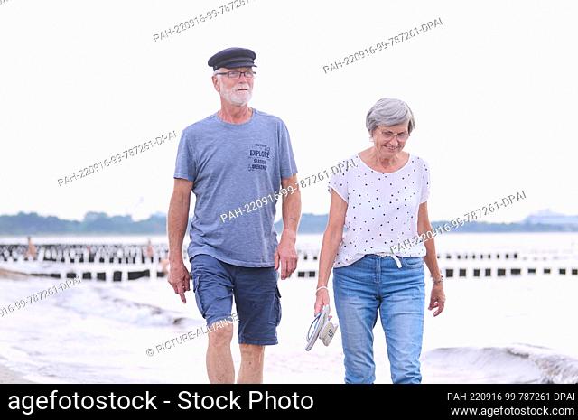 20 August 2022, Mecklenburg-Western Pomerania, Rostock: ILLUSTRATION - A retired couple is walking on the beach. Photo: Annette Riedl/dpa