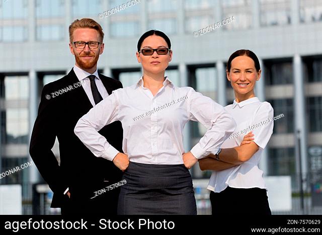 Group of happy business people with businesswoman leader on foreground. Woman in sunglasses posing with her arms akimbo
