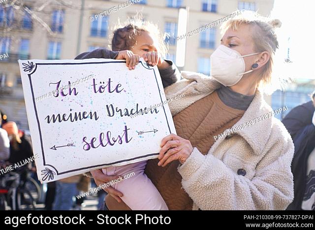 08 March 2021, Berlin: A sign with the inscription ""I kill my own dragon"" is carried by a woman with her daughter at a demonstration for International Women's...