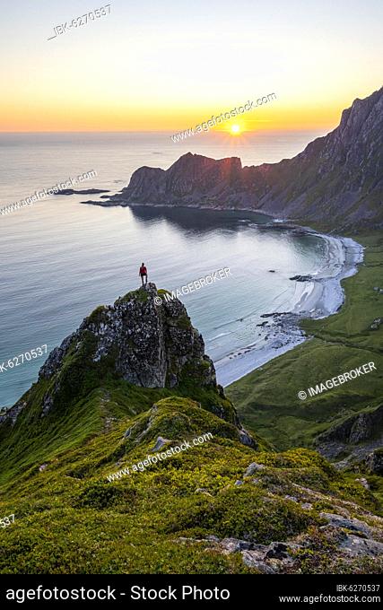 Sunset, hiker on rocks, cliffs, beach and sea, behind summit of mountain Måtinden, near Stave, Nordland, Norway, Europe