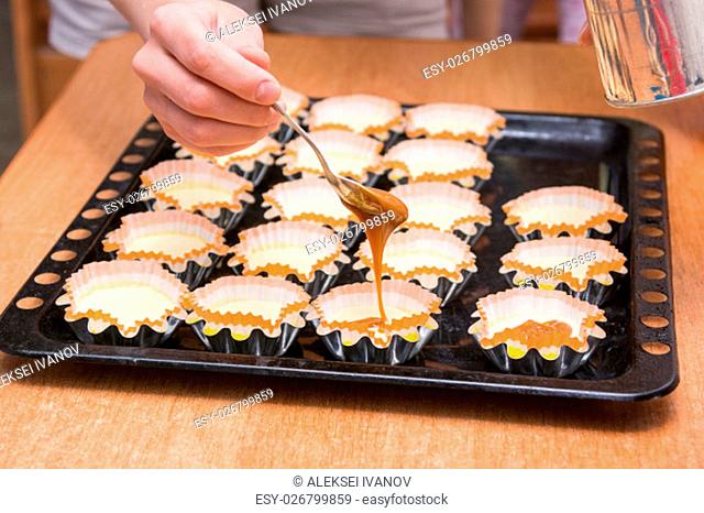 Boiled condensed milk added to raw cupcakes workpiece lying on a baking sheet