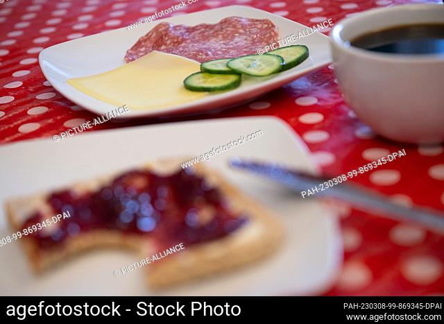 ILLUSTRATION - 06 March 2023, Hesse, Gießen: A plate of sausage and cheese lies behind a plate of jam sandwiches. When asked about the ""most important meal""...