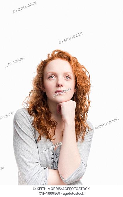 Single red haired young woman in studio on white background