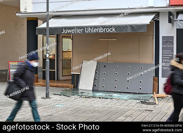 16 December 2021, Baden-Wuerttemberg, Friedrichshafen: A pane of bulletproof glass lies shattered on the ground outside a jewelry store as passersby walk by