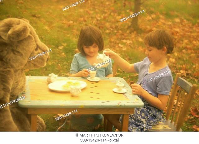Two girls having a tea party outdoors