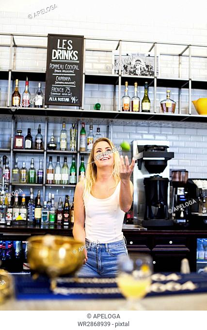Happy woman juggling at counter in cafe