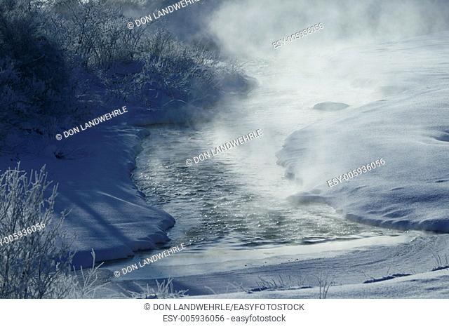 Rising mist from a warm river surrounded by snow covered fields on a cold morning, Stowe, Vermont, USA