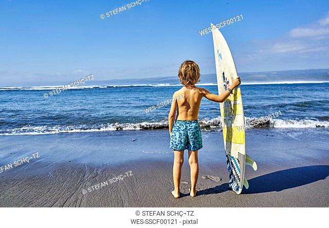 Chile, Pichilemu, boy standing at the sea with surfboard