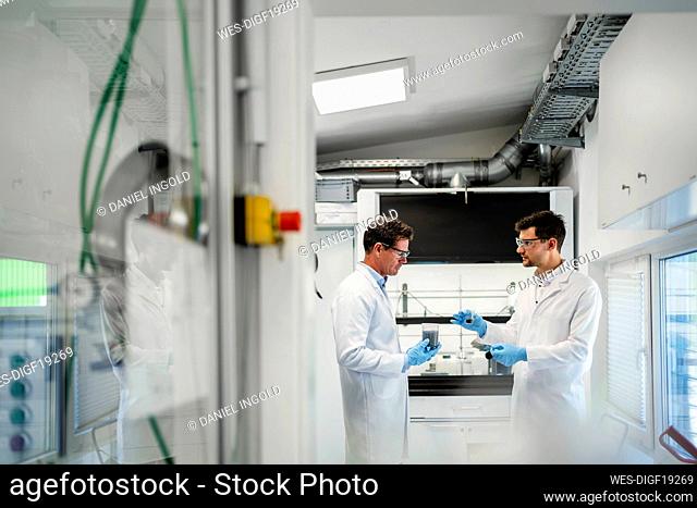 Mature scientist with colleague discussing over thermolysis experiment