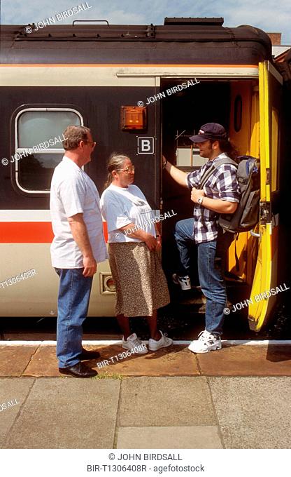 Mother and father saying goodbye to teenage son getting on train