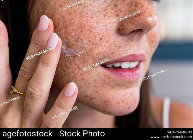 Hand of woman applying moisturizer on face