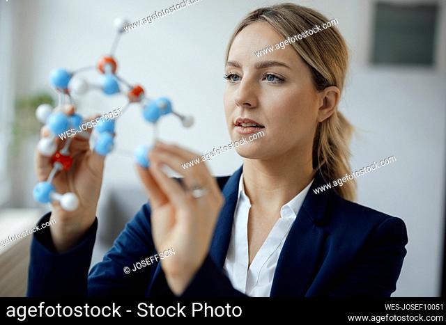 Businesswoman examining molecular model in office