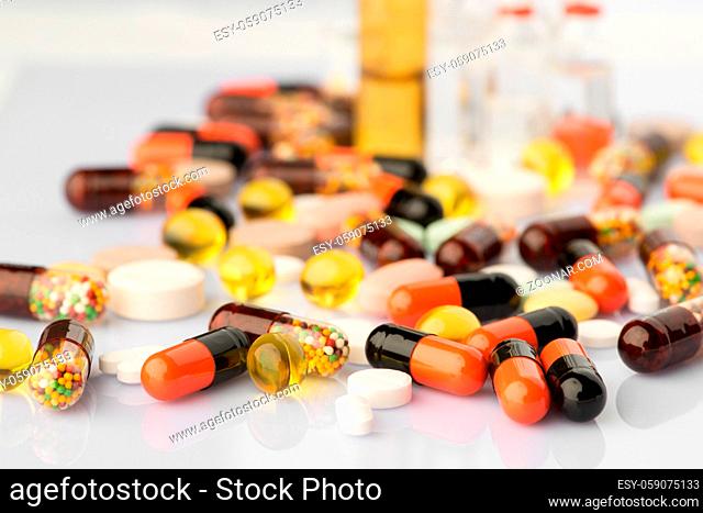 multi-colored tablets and capsules with reflection on blurred background