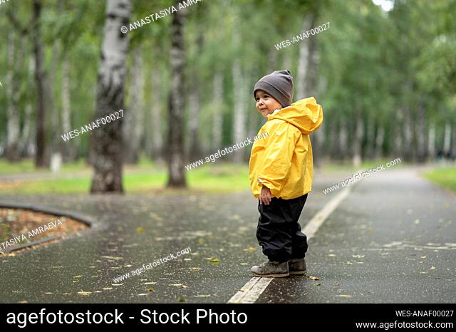 Baby boy wearing yellow rain jacket on road