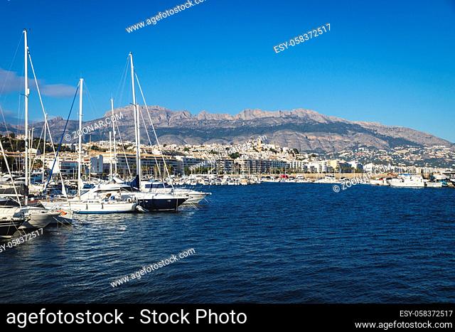 Boats at the port of Altea with view on mountain range with old city and cathedral on cloudless sunny day, Altea, Costa Blanca, Spain