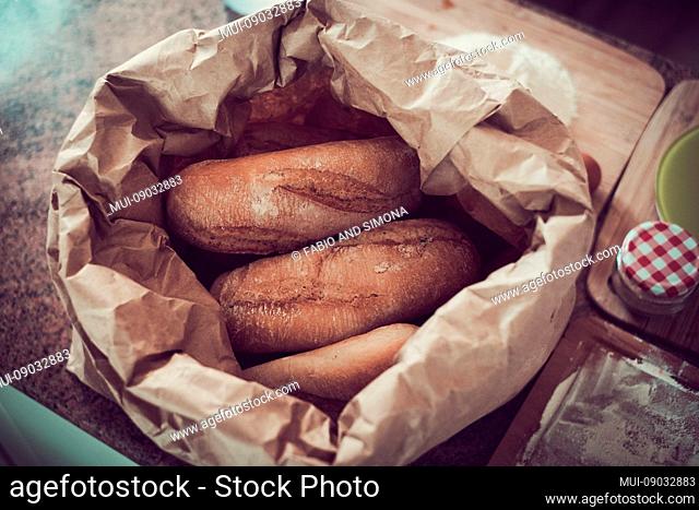 Bakery - gold rustic crusty loaves of bread and buns on country table - Open paper bag with bread - background. Still life captured from above