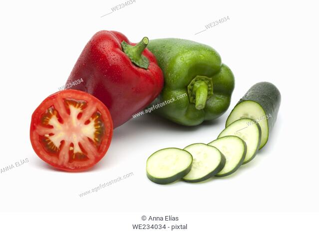 summer vegetables red bell pepper green bell pepper, half a tomato and sliced cucumber on a white background