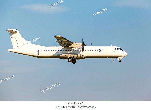 white passenger turboprop aircraft with the gear landing on blue sky background
