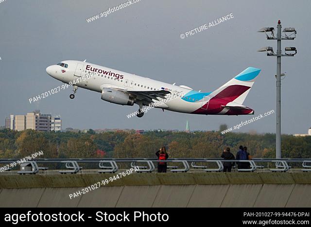 26 October 2020, Berlin: On the visitors' terrace of Tegel Airport, visitors watch a Eurowings aircraft take off. Scheduled flight operations in Tegel will...