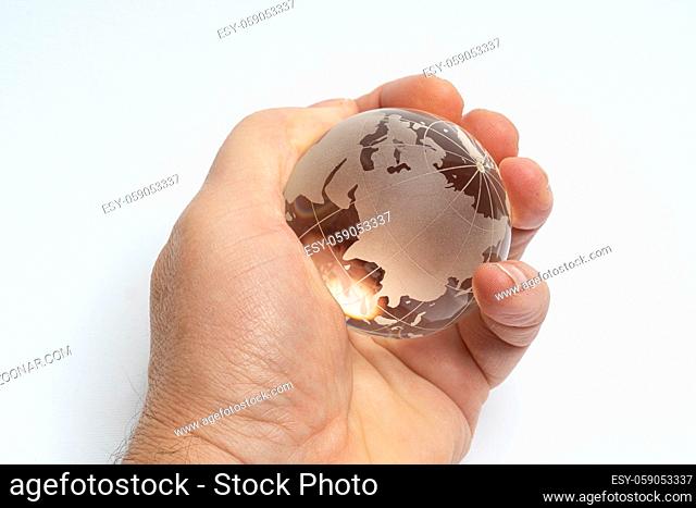 A male hand holds glass earth globe in the hand