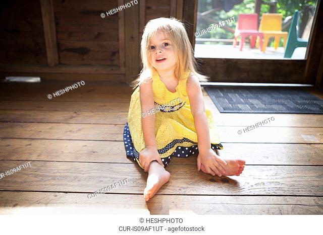 Female toddler sitting on wooden floor