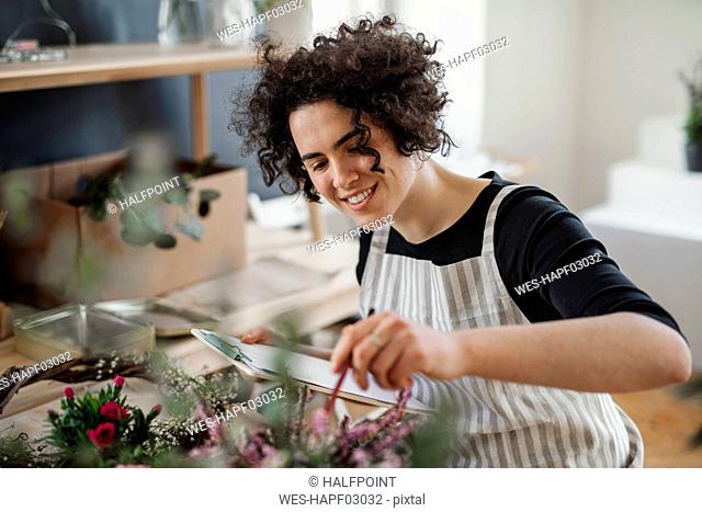 Smiling young woman with clipboard in a small shop with plants