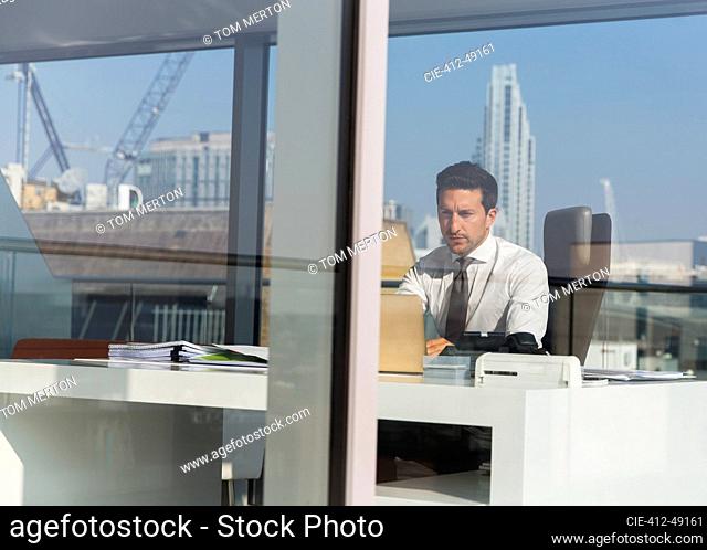 Focused businessman working in sunny, modern, urban office