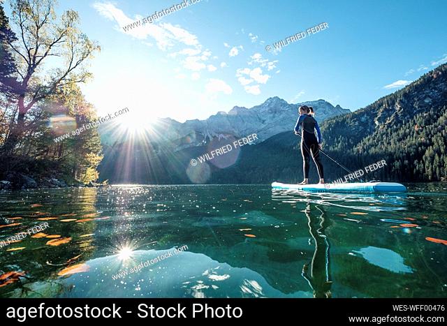 Germany, Bavaria, Garmisch Partenkirchen, Young woman stand up paddling on Lake Eibsee