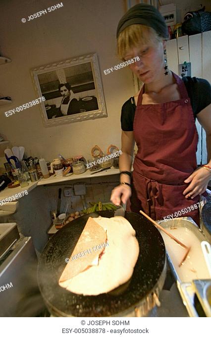 Young female chef prepares crepes in French restaurant in old section of Barcelona, Spain