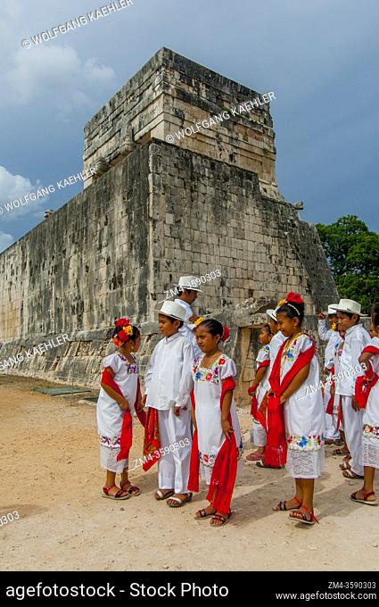 A group of Mayan children (dance group) visiting the great ball court in the Chichen Itza Archaeological Zone (UNESCO World Heritage Site) on the Yucatan...