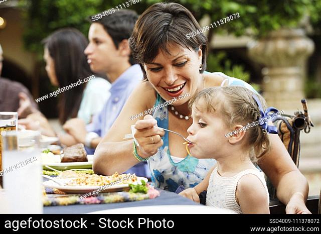 Young woman feeding her daughter