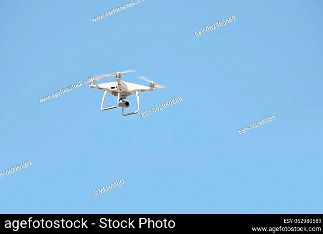 Big white drone hovering in a bright cloudless blue sky, Radio control helicopter with portable videocamera supply